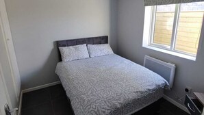 Ein Schlafzimmer mit Bett, Fenster und Heizkörper.