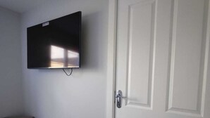 Ein Zimmer mit einer weißen Tür, einem wandmontierten Flachbildfernseher und einem dunklen Schrank.