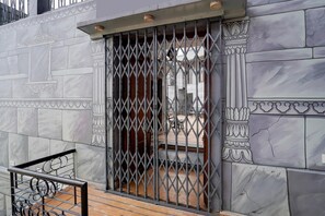 A gated entrance with a metal gate, a staircase, and a marble wall with decorative columns. - Palette Heritage Scindia Ghat (Varanasi)