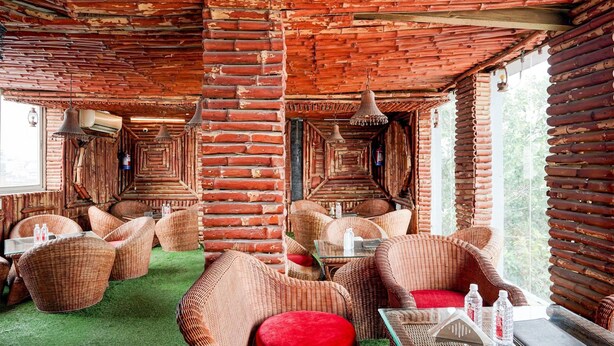 Ein rustikales Interieur mit Korbmöbeln, grünem Teppich und einer Ziegeldecke.