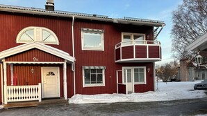 Un edificio rojo de dos pisos con un porche blanco y un balcón.