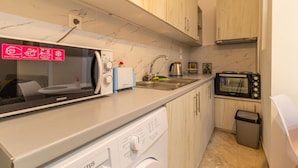 Una cocina compacta con microondas, tostadora y lavabo.