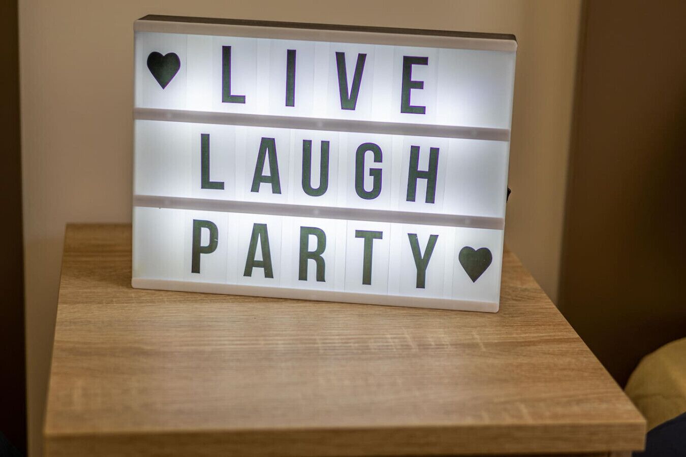 A lighted sign with the words "LIVE LAUGH PARTY" on a wooden surface.
