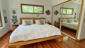 A bedroom with a wooden bed, white bedding, and a large mirror.