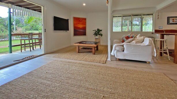 A spacious living area with a large TV, a painting, and a sofa.