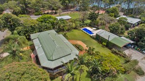 An aerial view of a property with multiple buildings, a swimming pool, and lush greenery.
