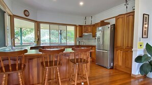 A kitchen with wooden cabinets, a stainless steel refrigerator, and a large window providing a view of greenery outside.