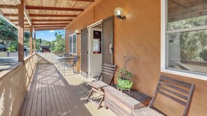 Un espacio al aire libre cubierto con una terraza de madera, una mesa con sillas y una planta en maceta.
