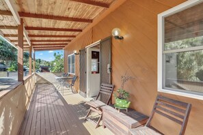 Un espace extérieur abrité, doté d’une terrasse en bois, d’une table avec des chaises et d’une plante en pot.