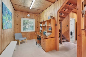 Un intérieur en bois comprenant un bureau, une chaise, une bibliothèque et un escalier.
