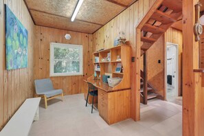 A wooden interior with a desk, chair, bookshelf, and a staircase.