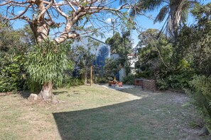 A spacious outdoor area with a large tree, a bench, and a brick wall.
