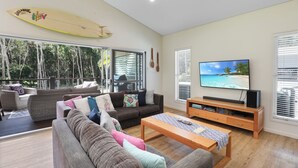 Una sala de estar moderna con un televisor grande, asientos cómodos y una decoración con una tabla de surf.