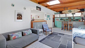 A cozy living room with a grey sofa, a blue armchair, and a dining area with a bar.