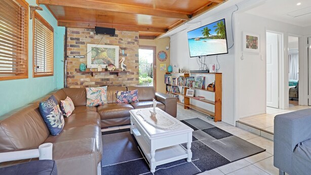 A living room with a brown leather sofa, a white coffee table, and a bookshelf filled with books.