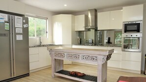 Una cocina moderna con armarios blancos, una isla de madera, electrodomésticos de acero inoxidable y un ventanal que proporciona luz natural.