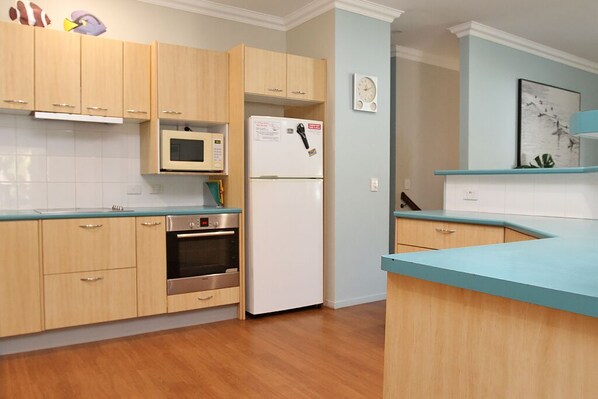 A modern kitchen with wooden cabinets, a microwave, a refrigerator, and an oven.