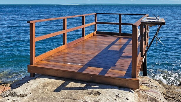 A wooden dock extending into a body of water with a clear sky.