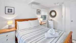 A neatly arranged bedroom with a bed, bedside tables, a dresser, and a mirror.
