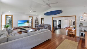 Ein modernes Wohnzimmer mit einem grauen Sofa, einem Flachbildfernseher und einem Surfbrett an der Wand.