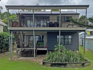 Een modern huis met twee verdiepingen, een balkon, een trap en een tuin.