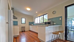 A modern kitchen with white cabinets, a microwave, and a window.