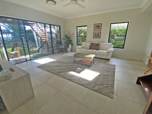 A spacious living room with a white sofa, a coffee table, and a large sliding glass door leading to a balcony.