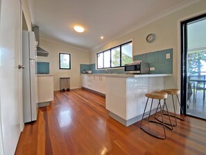 A modern kitchen with white cabinets, a microwave, and a window.