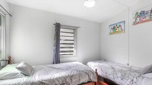 A room with two beds, a window with blinds, a painting on the wall, and a ceiling light. - Perfect for retired folk, Fisherman & Small families (Amity Point)