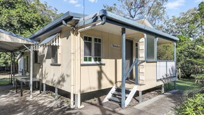 A small, single-story building with a covered porch, a nameplate, and a staircase leading to the entrance. - Perfect for retired folk, Fisherman & Small families (Amity Point)