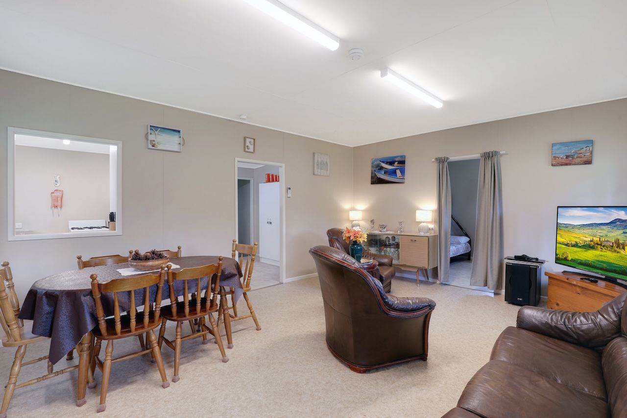 A living room with a dining area, a sofa, a TV, and a staircase leading to another room.