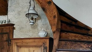 Puinen, kierremäinen portaikko, jossa on maalaishenkinen muotoilu, kiviseinä ja puuovi.