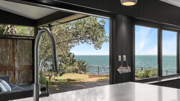Een moderne keuken met uitzicht op zee, een houten omheining en een hangend bord.