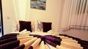 Una habitació d'hotel amb llit, almoinos, un quadre a la paret i una finestra amb cortines.