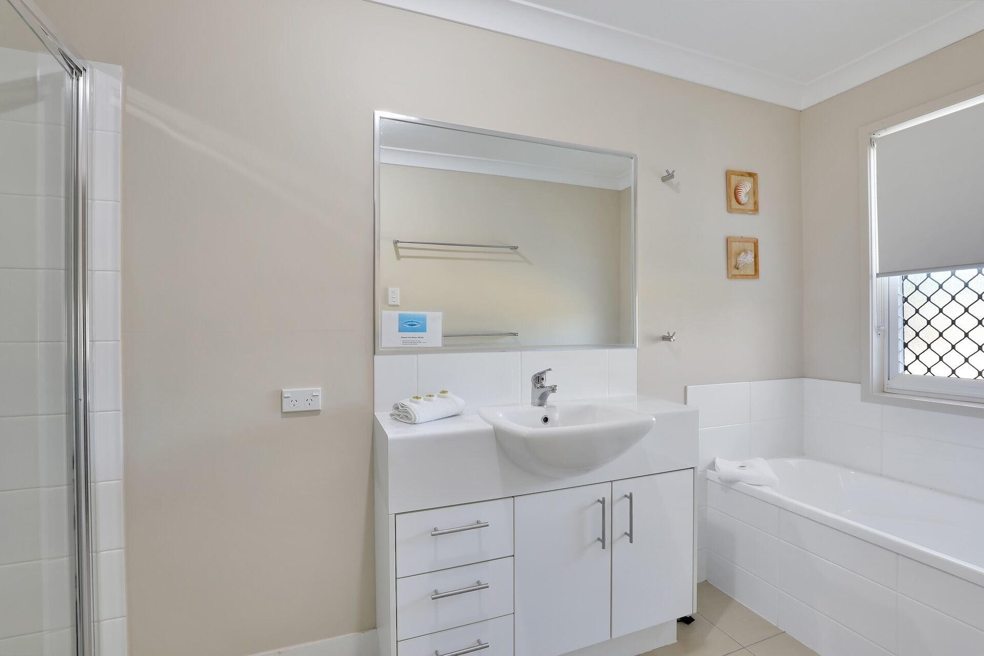 Un baño con lavamanos, espejo, toallero y bañera.