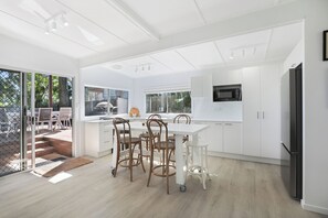 A modern kitchen with white cabinetry, a black refrigerator, and a dining area with a table and chairs. - Amity Waterfront, on 1/2 Acre with slate floors throughout (Amity Point)