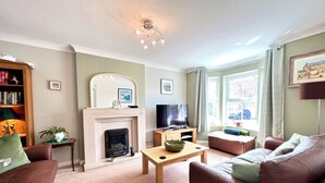 A living room with a fireplace, a television, a sofa, and a coffee table. - Harefield (Morpeth)