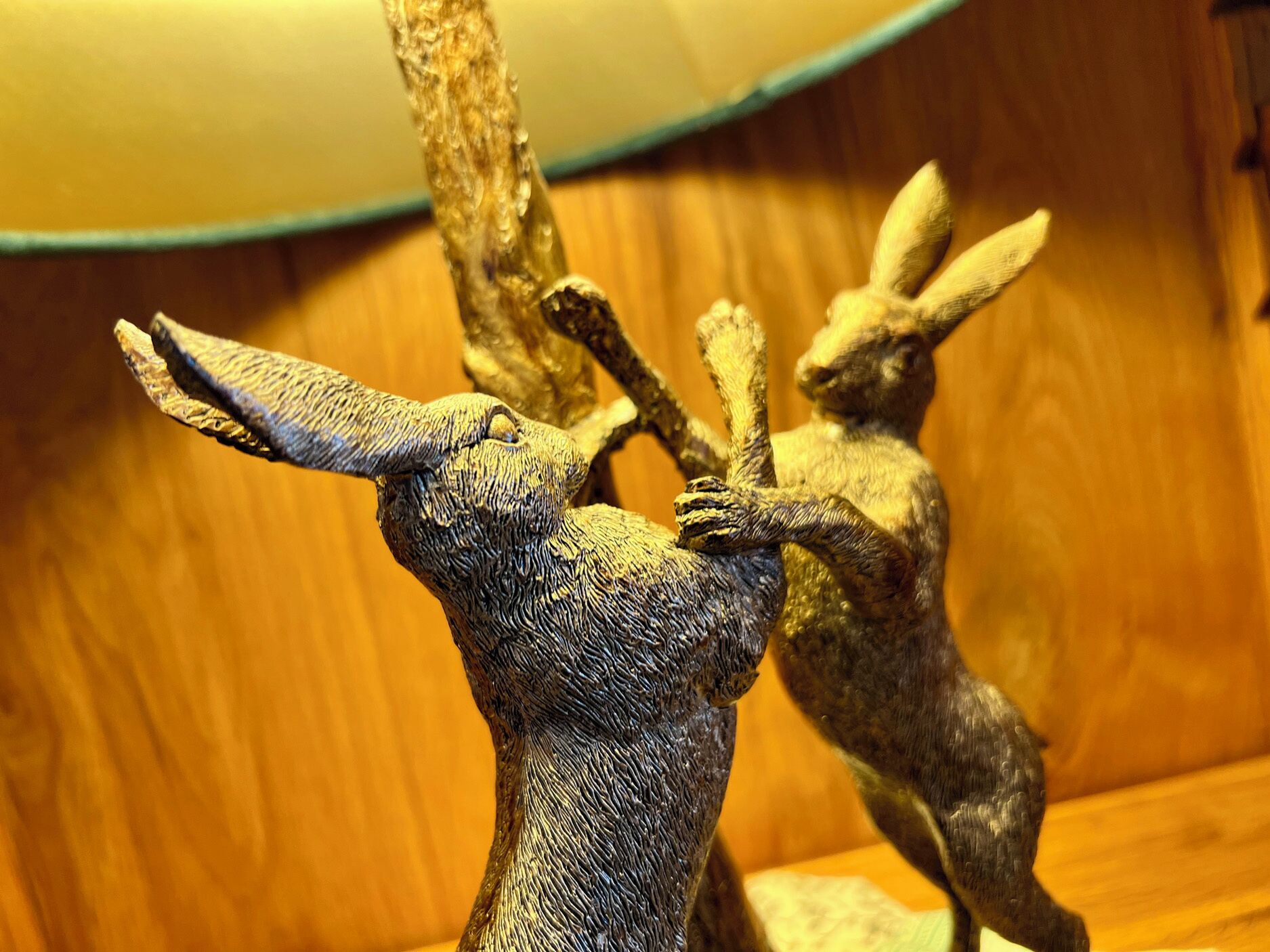 Une sculpture représentant un cerf avec des bois, placée sur une surface en bois.