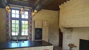 A kitchen with a large island, wooden cabinets, a built-in oven, and a stone wall.