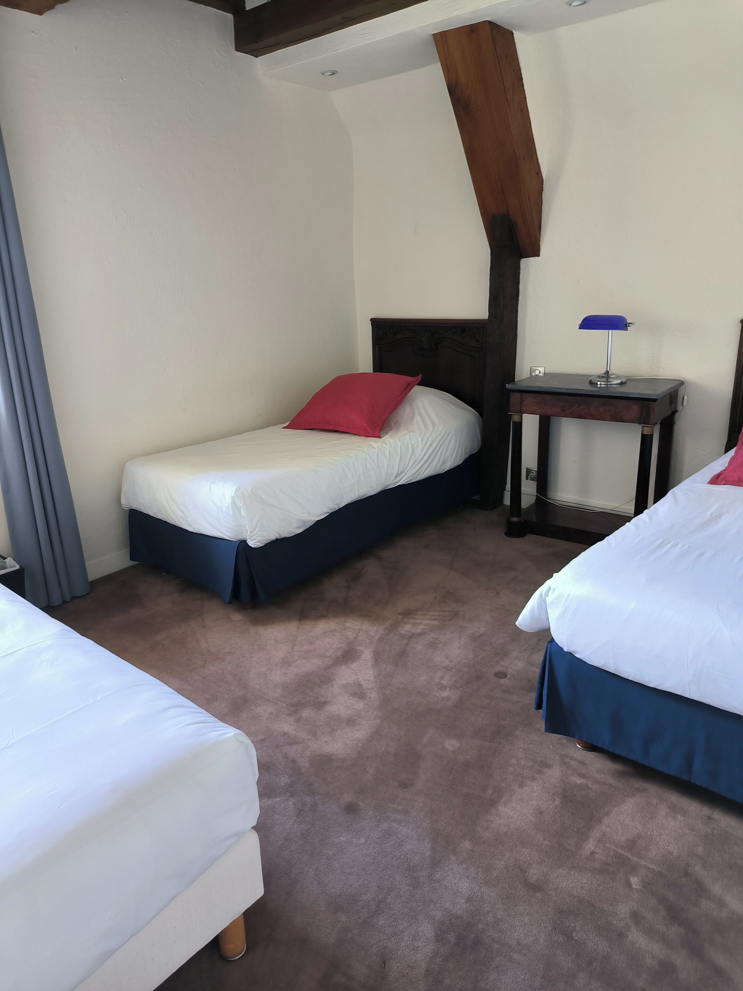 A bedroom with two beds, a nightstand, and a lamp.