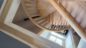 A spiral staircase with wooden steps and handrails, leading to an upper floor.