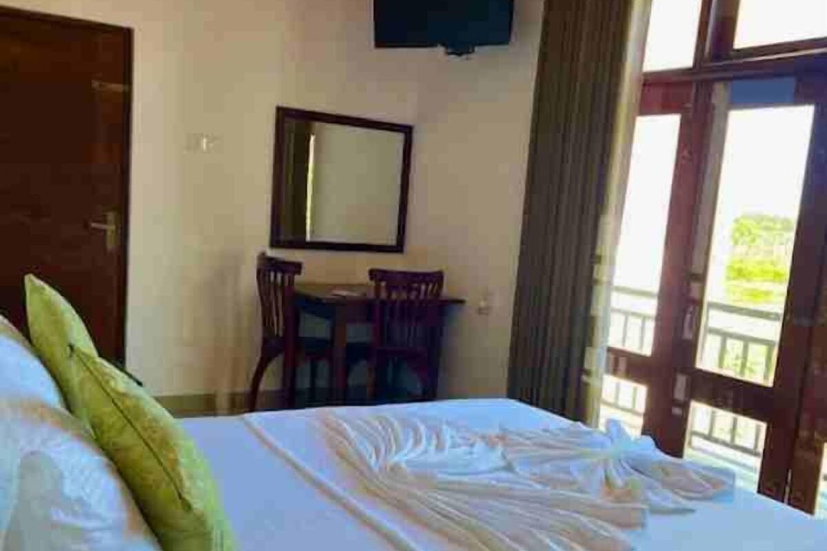A hotel room with a bed, a desk, a chair, a television, and a window with curtains.