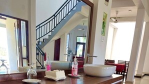A wooden counter with a sink, a bottle of hand soap, and a glass vase. - Kamatha Hotel & Restaurant (Ambalantota)