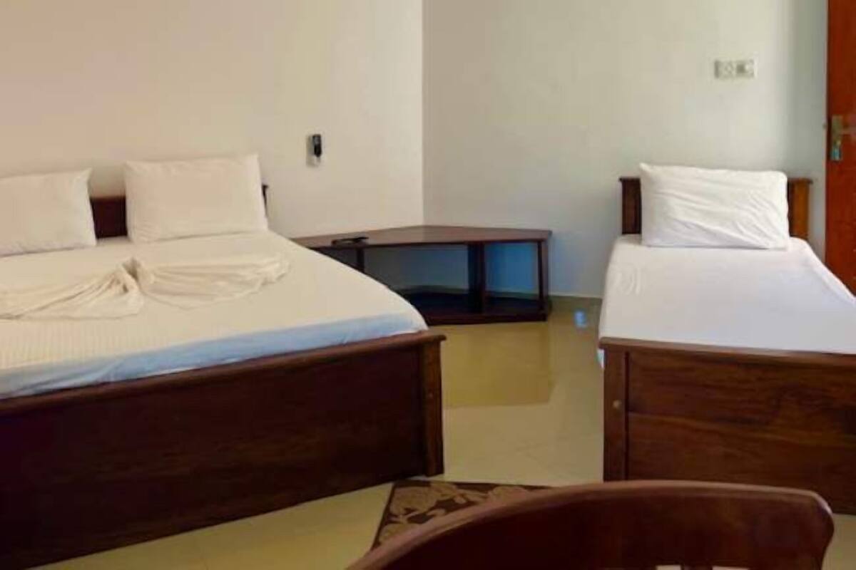 A hotel room with two wooden beds, a small wooden table, and a door.