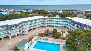 A hotel with a pool area, multiple balconies, and a view of the ocean. - The Salty Mint - Resort Condo w/ Pools, Hot Tub, & Beach Access – Sleeps 7 (Kure Beach)