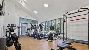 A gym with cardio machines, weightlifting equipment, and a pull-up bar. - The Salty Mint - Resort Condo w/ Pools, Hot Tub, & Beach Access – Sleeps 7 (Kure Beach)