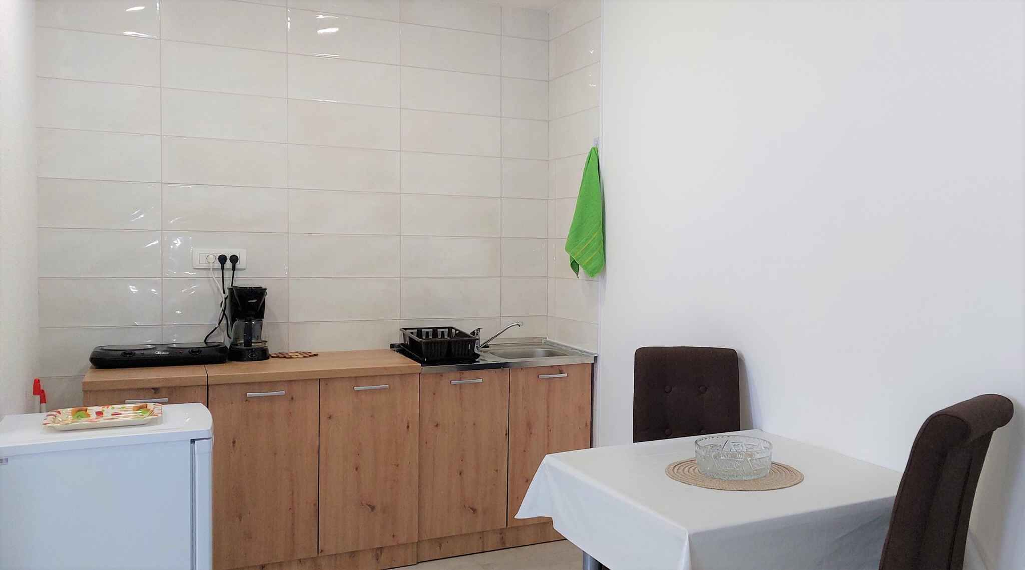 Een kleine keuken met een koffiezetapparaat, een spoelbak en houten kastjes.