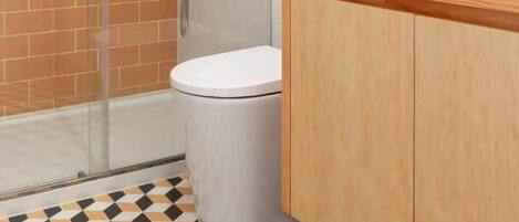 A bathroom with a glass shower enclosure, a white toilet, and a wooden vanity with a mirror.