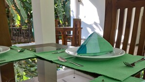 A dining table set with a green placemat, a white plate, and a blue napkin. - Wild Safari Nest Udawalawe  (Udawalawe)