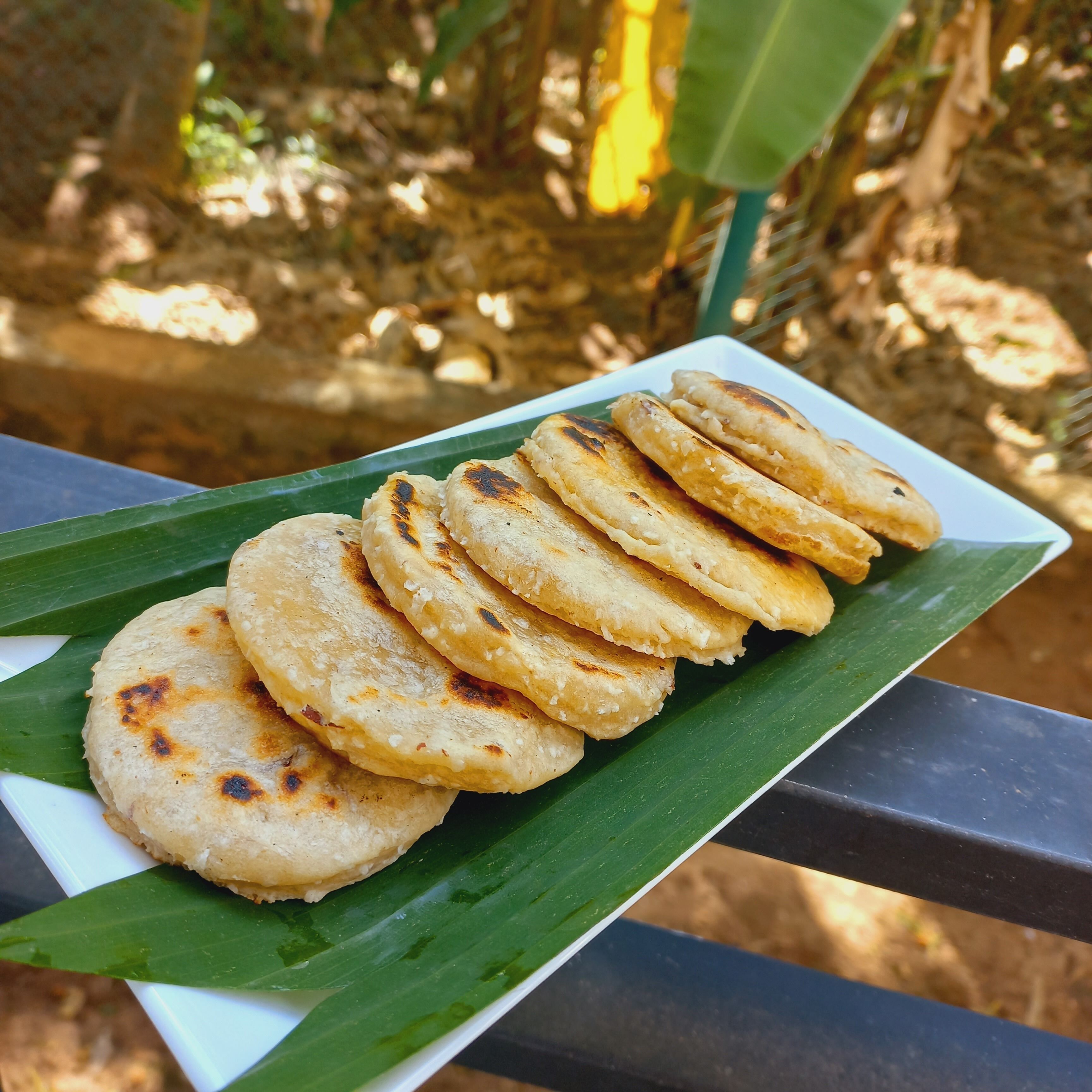 A plate of flatbreads on a white plate with a green leaf underneath, placed on a metal railing.